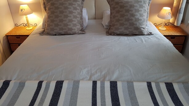 A neatly made bed with two pillows, two bedside lamps, and a striped area rug. - Cherry End bed and breakfast  (Chichester)