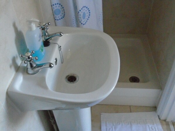 A bathroom with a white sink, a faucet, and a soap dispenser. - Cherry End bed and breakfast (Chichester)