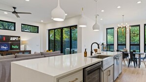 A modern kitchen with a large island, built-in appliances, and pendant lighting. - 2605 E 4th xxxxxxxxx (Austin)