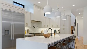 A modern kitchen with white cabinetry, stainless steel appliances, and pendant lighting. - 2605 E 4th xxxxxxxxx (Austin)