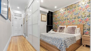 A bedroom with a wooden bed, a patterned wall, and a hallway with white doors. - Duffotel Paddington LUXE (Paddington)