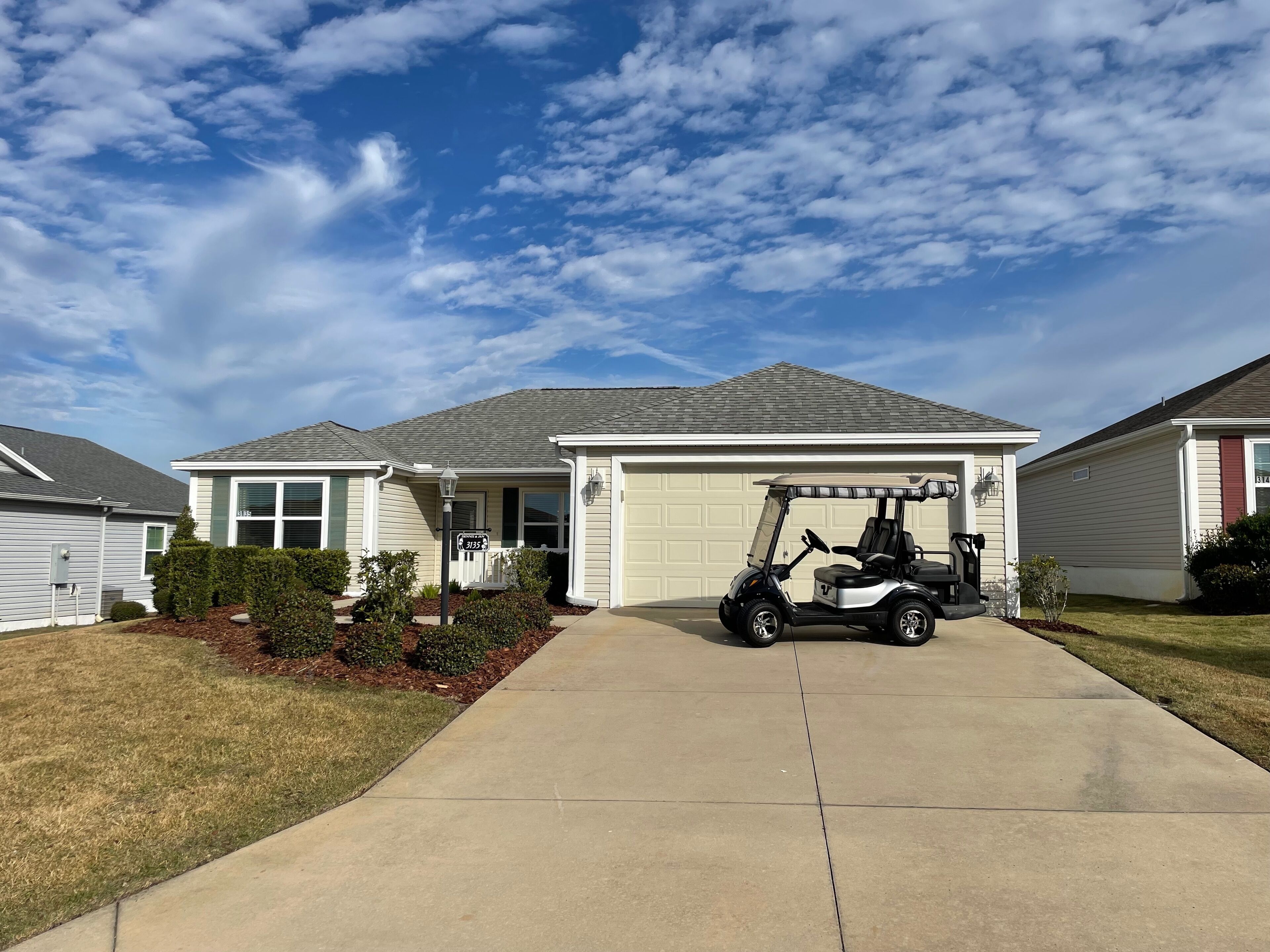 A residential home with a garage, a driveway, and a golf cart parked in front.
