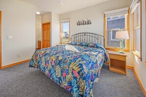 A bedroom with a large bed, a wooden wardrobe, a window with a view, and a wall-mounted decoration. - Soundfront w/ Hot Tub, Media Room, Windsports Access, Community Pool/Boat Dock (Avon)