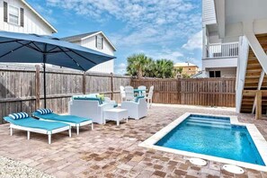 Un jardin avec une piscine, des chaises longues et une clôture en bois.