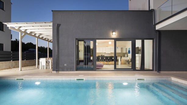 A modern poolside area with a covered seating area and a view into the house. - Elegant Villa Sole with private pool and sauna  (Pomer)