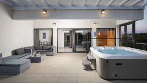 A modern outdoor living area with a hot tub, seating, and a glass door leading to a balcony. - Elegant Villa Sole with private pool and sauna  (Pomer)