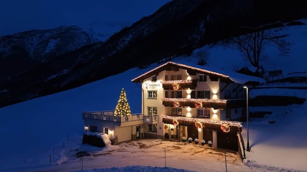 A hotel with a balcony, a Christmas tree, and snow-covered surroundings.