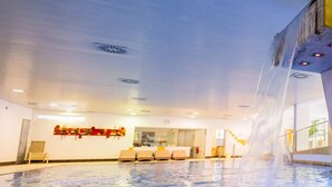 An indoor swimming pool with a water feature, seating area, and a visible reception desk. - Residenz am Lech - Wohnung 1 (Steeg, Lechtal)