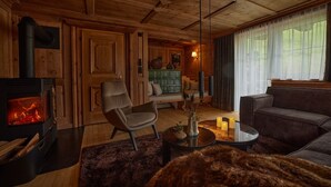 A cozy living room with a fireplace, a sofa, a chair, and a coffee table. - Residenz am Lech - Wohnung 1 (Steeg, Lechtal)