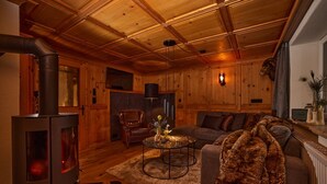 A cozy living room with a wood-burning stove, a sofa, a coffee table, and a fireplace. - Residenz am Lech - Wohnung 4 (Steeg, Lechtal)
