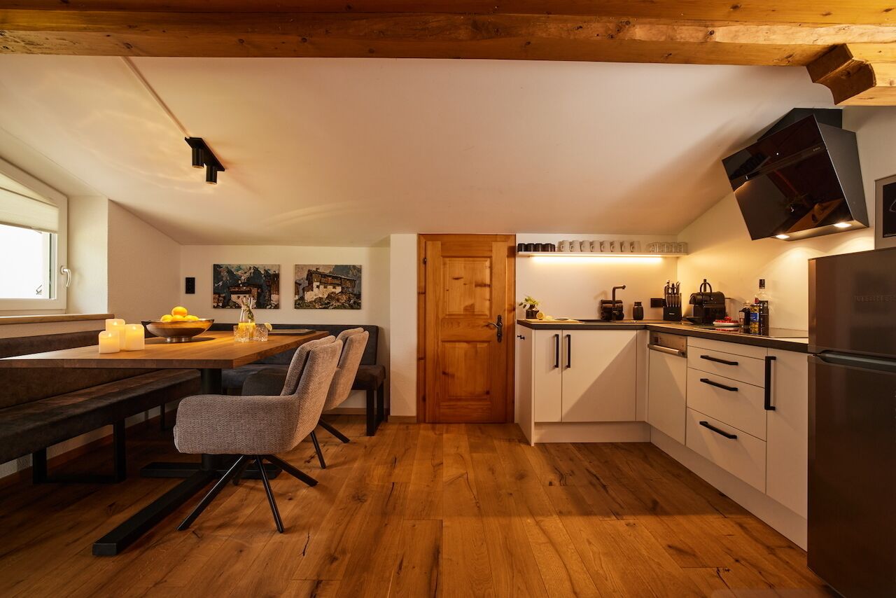 Een moderne keuken met houten vloeren, een eethoek met een bank, en een inbouwoven.