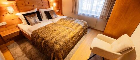 Una habitación acogedora de madera con una cama, una silla y un ventanal con cortinas.