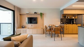 Un espacio habitable moderno con sofá, comedor, cocina y televisor montado en la pared.