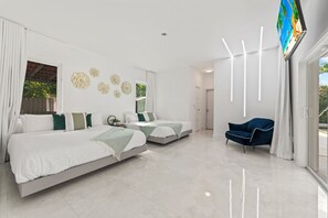 Two single beds with white bedding and green throw pillows, situated parallel to each other, offer a comfortable sleeping space.