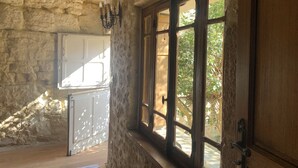 A rustic stone interior with a large window, a wooden door, and a white cabinet.
