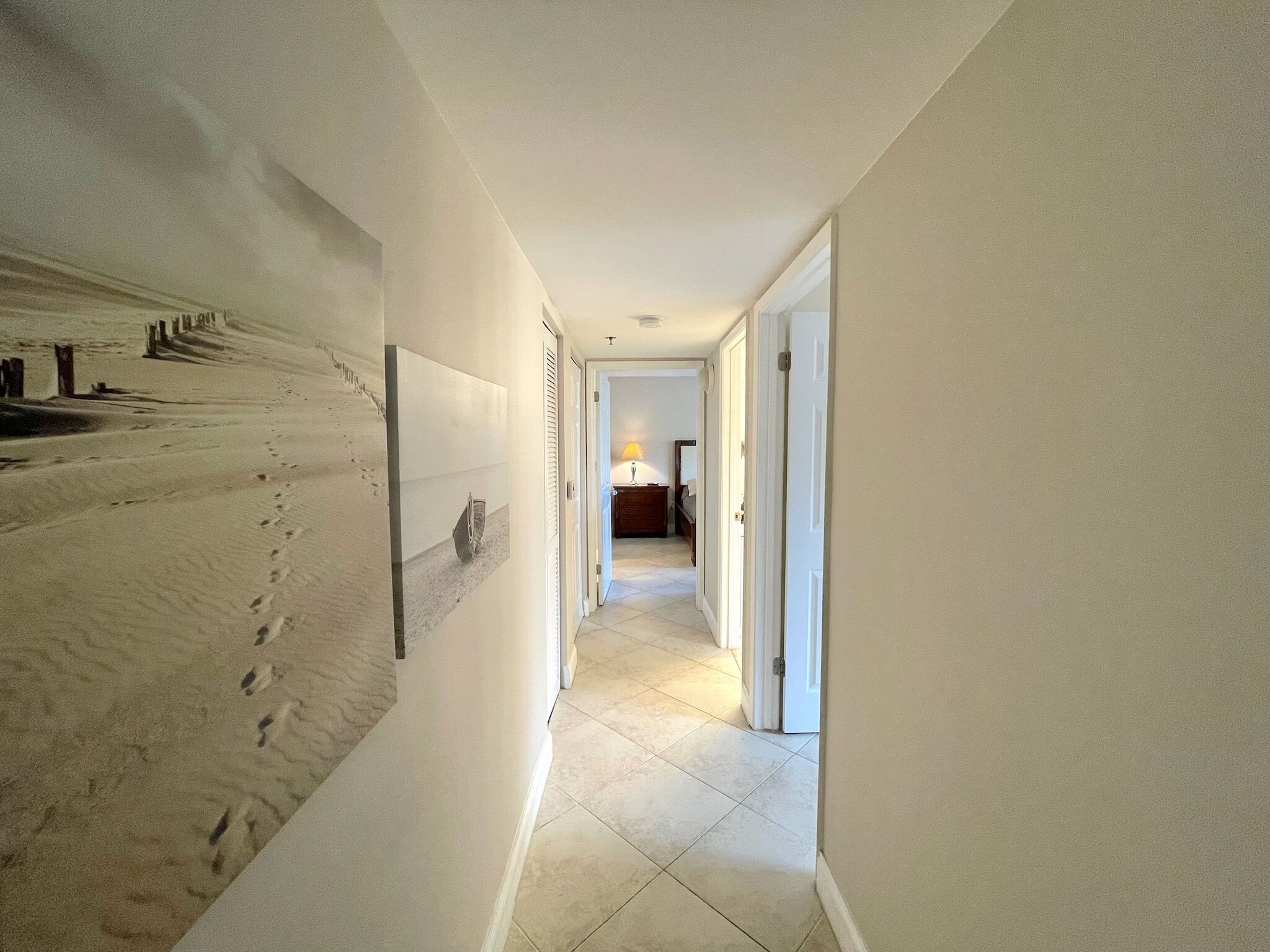 A hallway with a large wall mural, white walls, and a tiled floor.