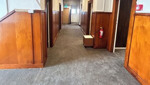 A corridor with wooden paneling and carpeted floors, leading to multiple doors. - The Blackhorse Hotel (Christchurch)