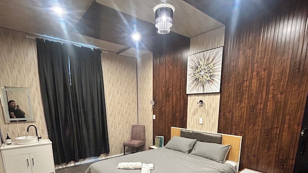 A modern bedroom with a large bed, a bedside table, a chair, a wardrobe, and a mirror. - The Blackhorse Hotel (Christchurch)