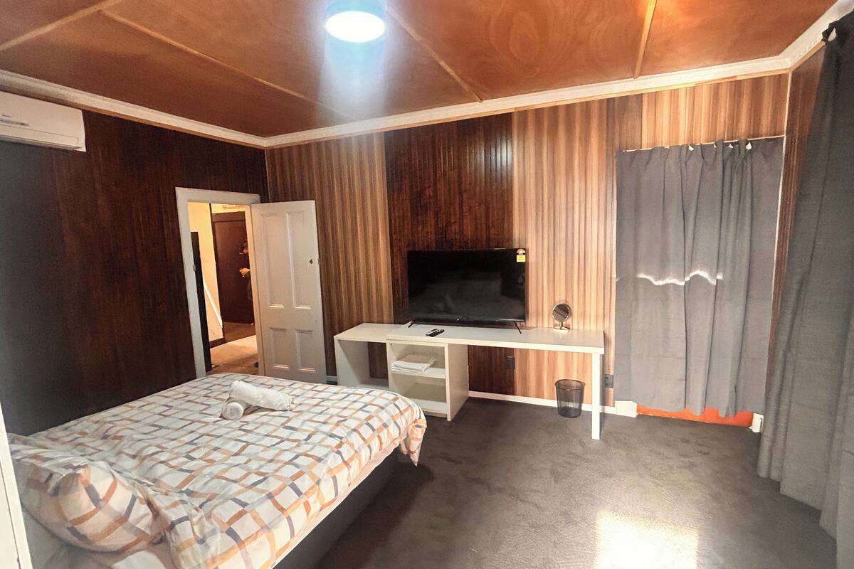 Un dormitorio con cama, escritorio, televisor y zona de ducha.