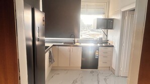 A compact kitchen with a refrigerator, sink, and microwave. - The Blackhorse Hotel (Christchurch)