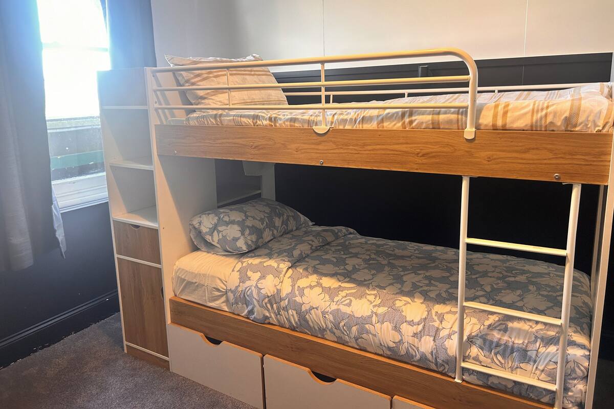 Una cama litera con una cama inferior y un estante para guardar objetos debajo.