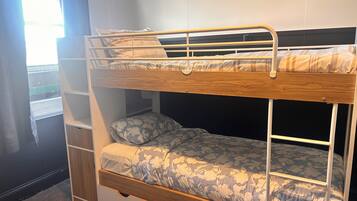 Una cama litera con una cama inferior y un estante para guardar objetos debajo.