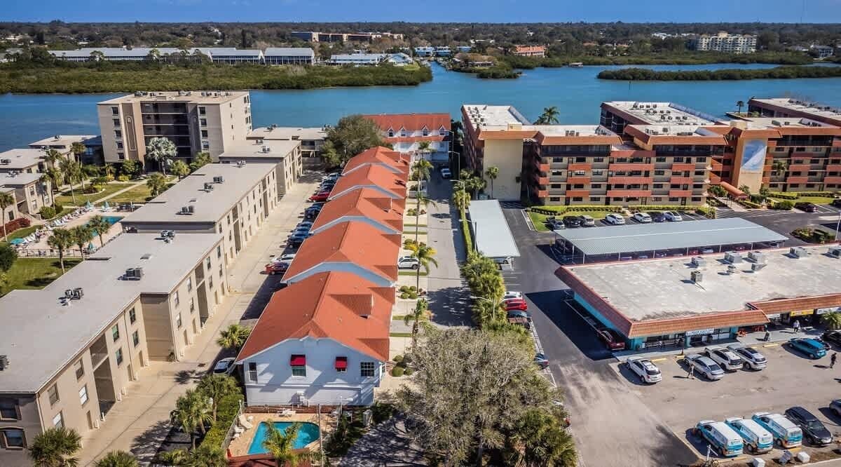 Un hotel con una larga hilera de habitaciones, un estacionamiento y vistas a un cuerpo de agua.