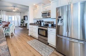 A modern kitchen with stainless steel appliances, white cabinetry, and a dining area with a table and chairs.