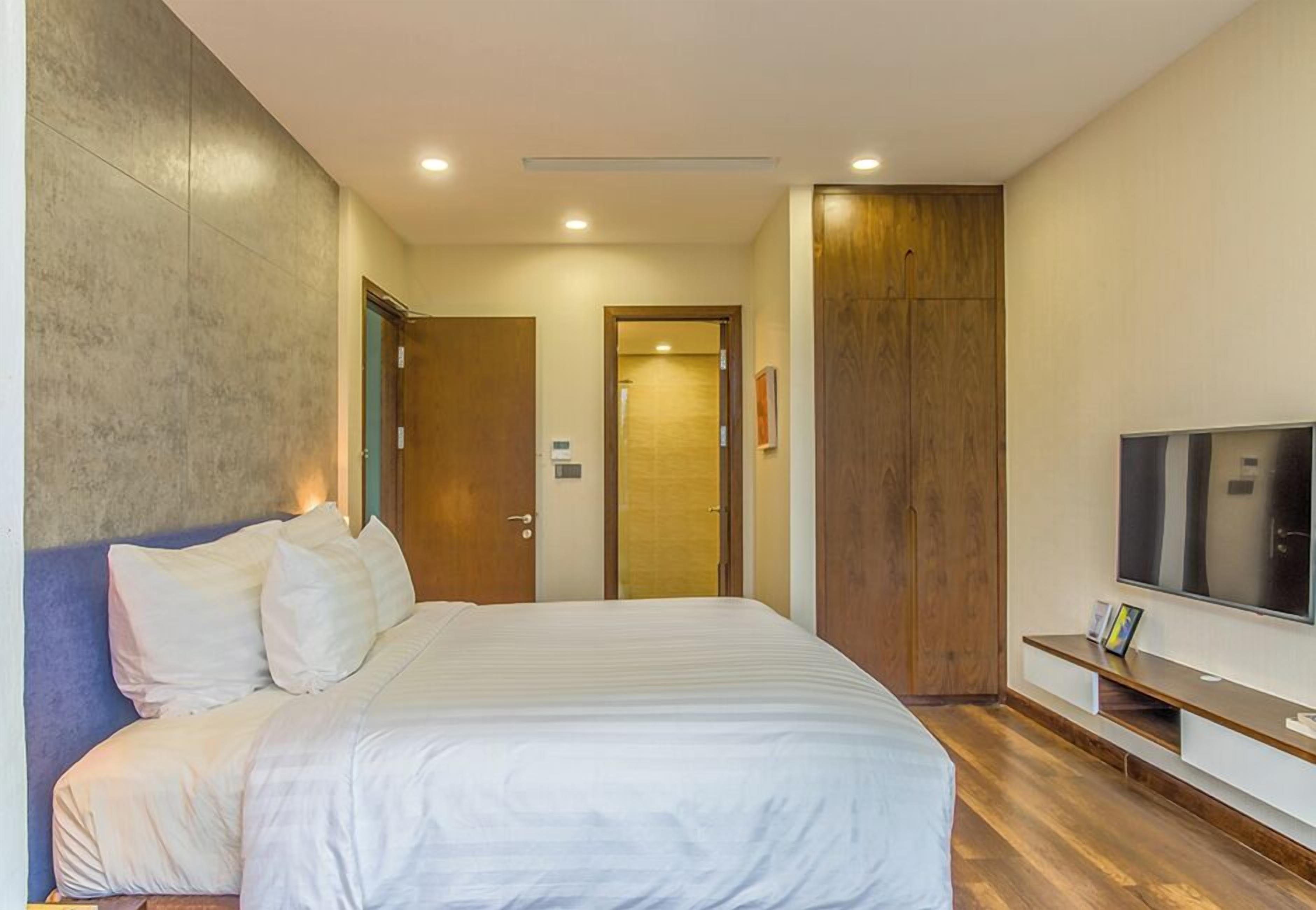 Habitación de hotel con una cama grande, televisión y armario de madera.