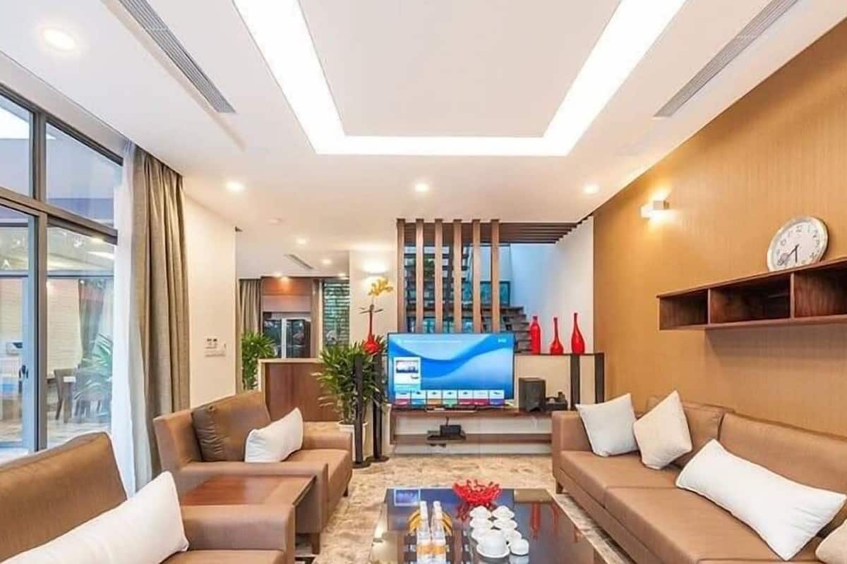 A modern living room with a flat-screen TV, sofas, a coffee table, and a large window.