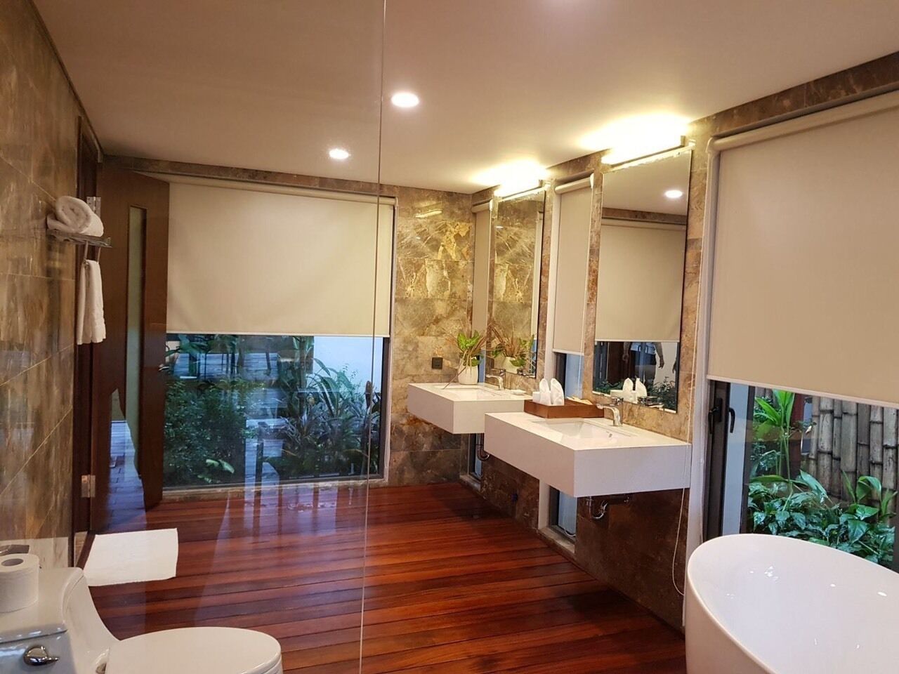 Ein modernes Badezimmer mit Holzboden, zwei Waschbecken, einem großen Spiegel und einer Badewanne.