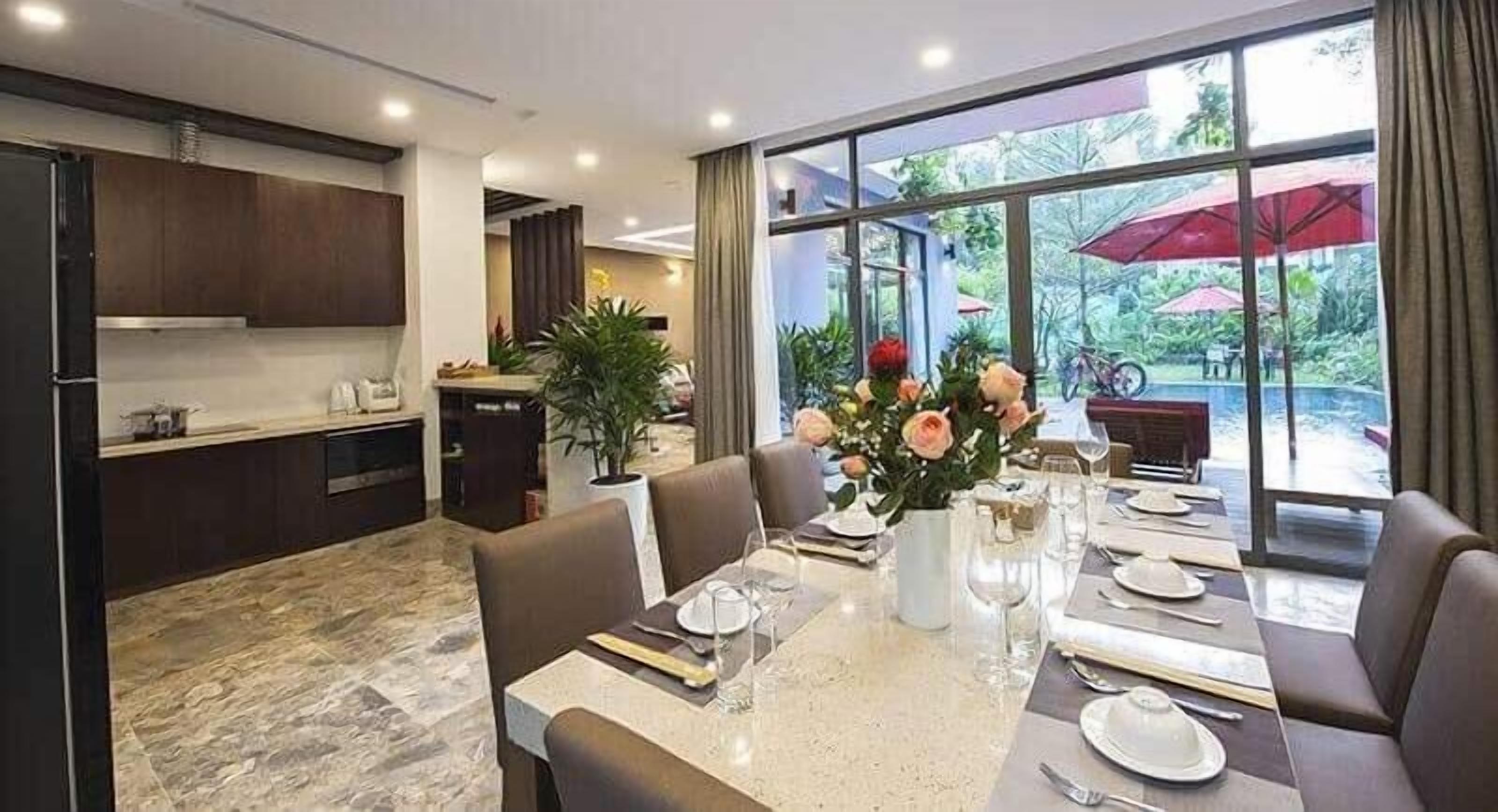 A modern dining area with a marble table, brown leather chairs, and a view of the outdoors through large windows.