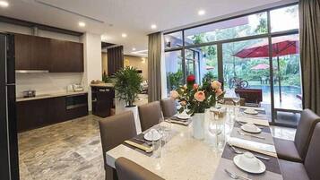 A modern dining area with a marble table, brown leather chairs, and a view of the outdoors through large windows.