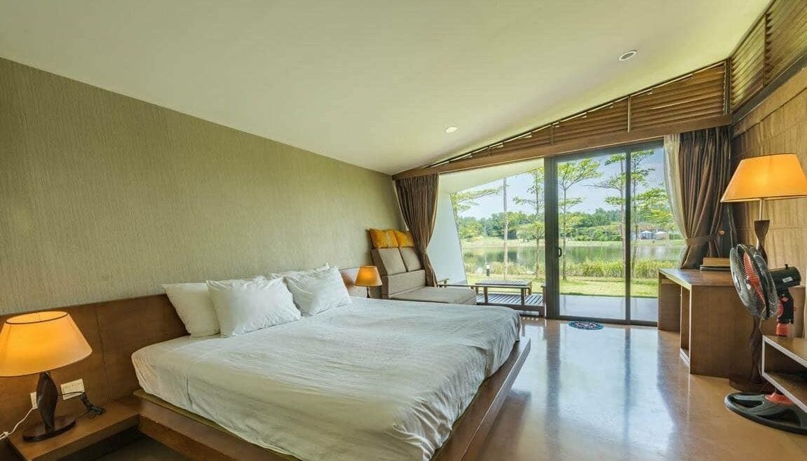 Una habitación de hotel con una cama grande, una zona de estar con vistas y un escritorio con lámpara.