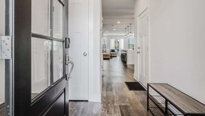 A hallway with a bench, a door, and a view into a living area with a sofa and a coffee table. - Bethany Beach * New Modern Luxurious Townhome - 4 (Ocean View)