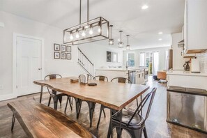 Eine moderne Küche mit Holztisch, Metallstühlen und Pendelleuchten.