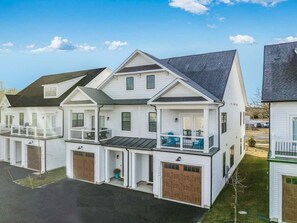 Eine Reihe weißer zweigeschossiger Häuser mit angebauten Garagen, einem zentralen Balkon und blauem Himmel.