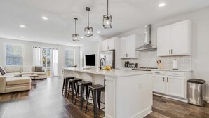 A modern kitchen with white cabinets, a central island, bar stools, and pendant lighting. - Bethany Beach * New Modern Luxurious Townhome - 4 (Ocean View)