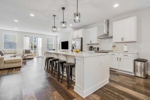 A modern kitchen with white cabinets, a central island, bar stools, and pendant lighting. - Bethany Beach * New Modern Luxurious Townhome - 4 (Ocean View)