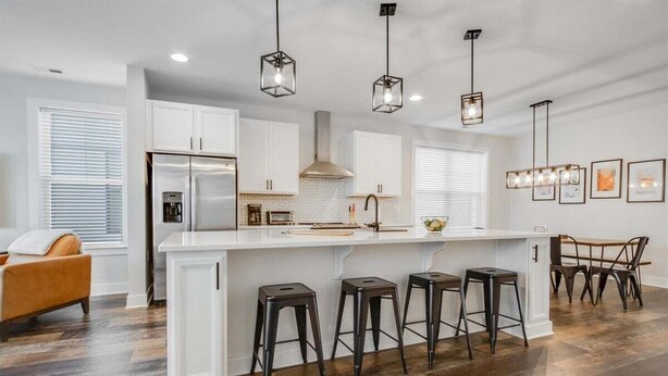 A modern kitchen with white cabinetry, a stainless steel refrigerator, a central island with stools, and pendant lighting. - Bethany Beach * New Modern Luxurious Townhome - 4 (Ocean View)