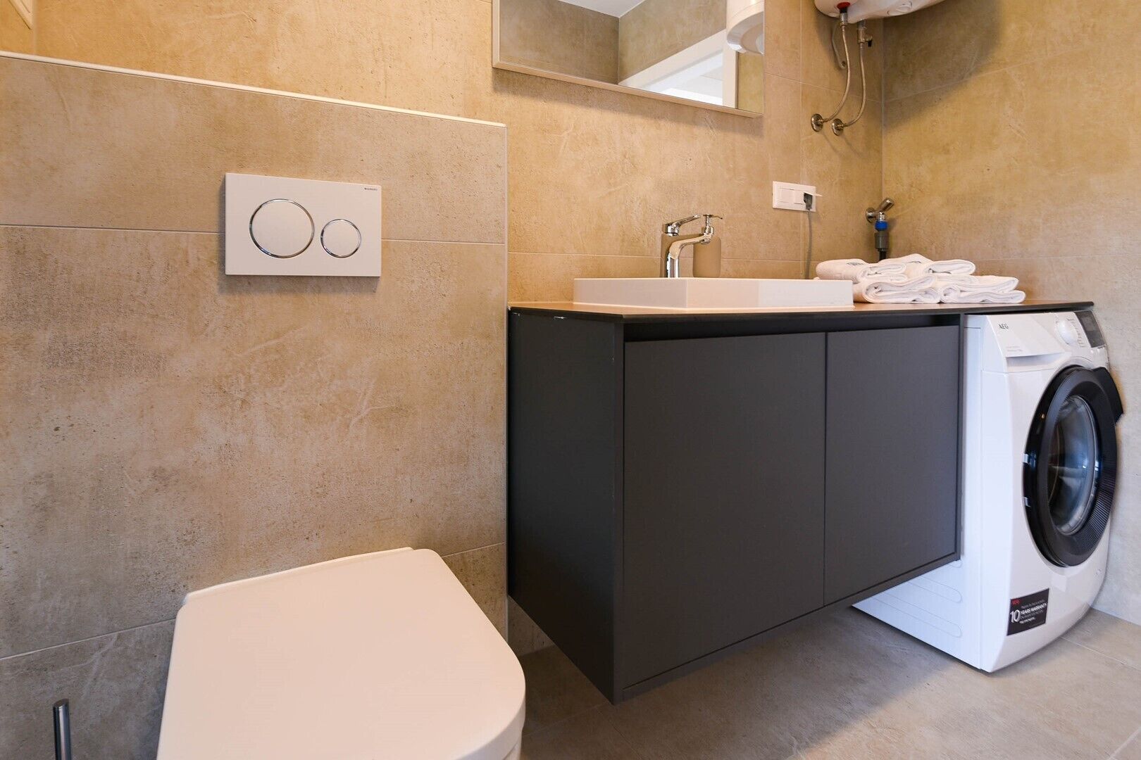 Ein modernes Badezimmer mit Toilette, Waschbecken und Waschmaschine.