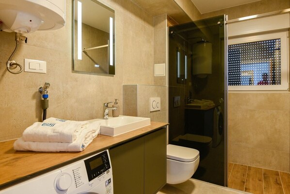 A modern bathroom with a sink, mirror, and toilet.
