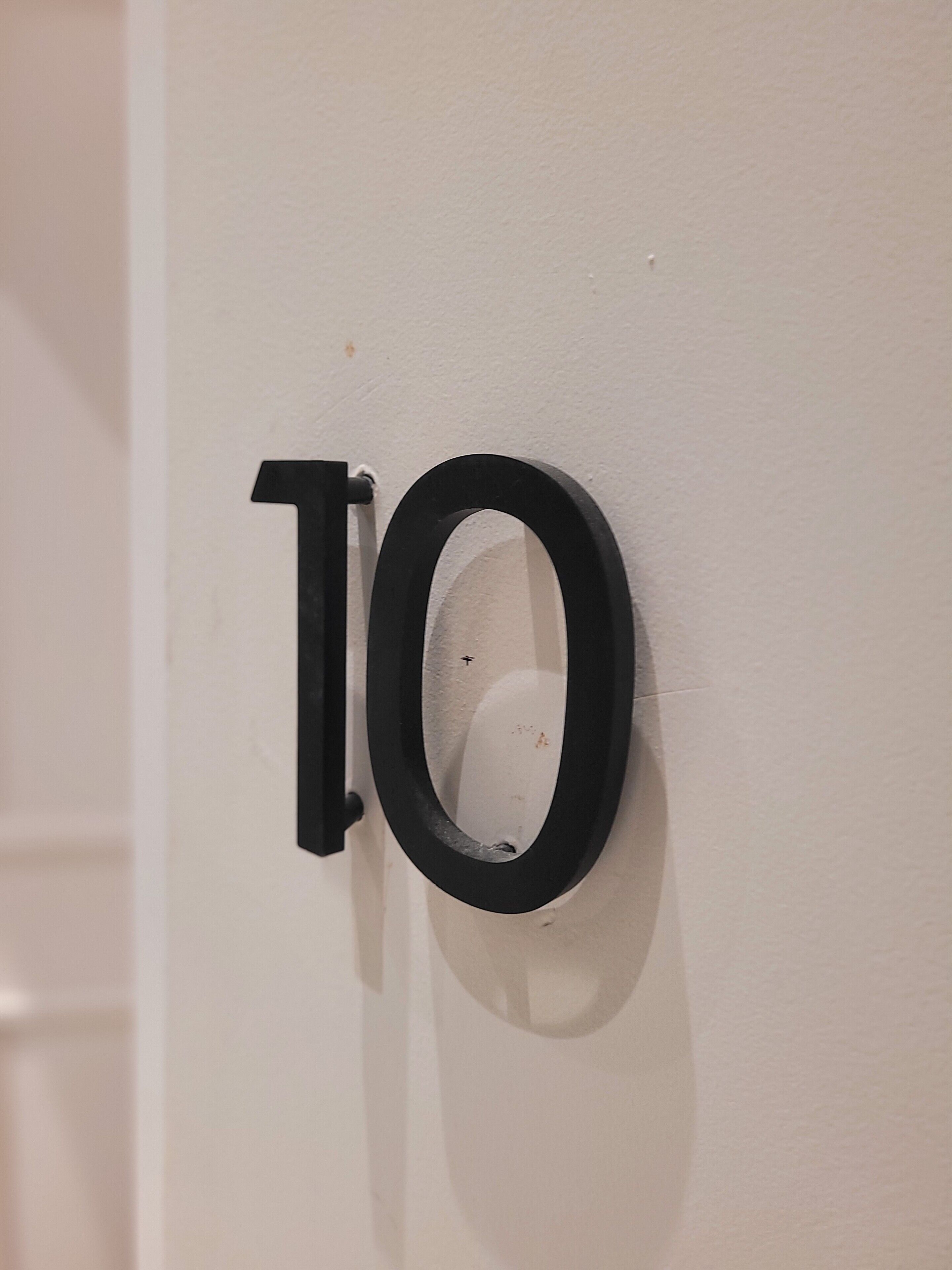 Eine weiße Tür mit einem schwarzen Schild mit der Nummer 10.