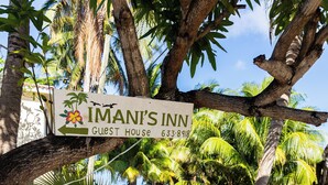Une enseigne indiquant l’emplacement d’Imani’s Inn, une maison d’hôtes, avec un palmier au premier plan.