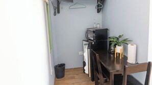 Une petite cuisine équipée d’un four à micro-ondes, d’un grille-pain et d’une machine à café. On y trouve une table en bois avec des chaises et une plante en pot.