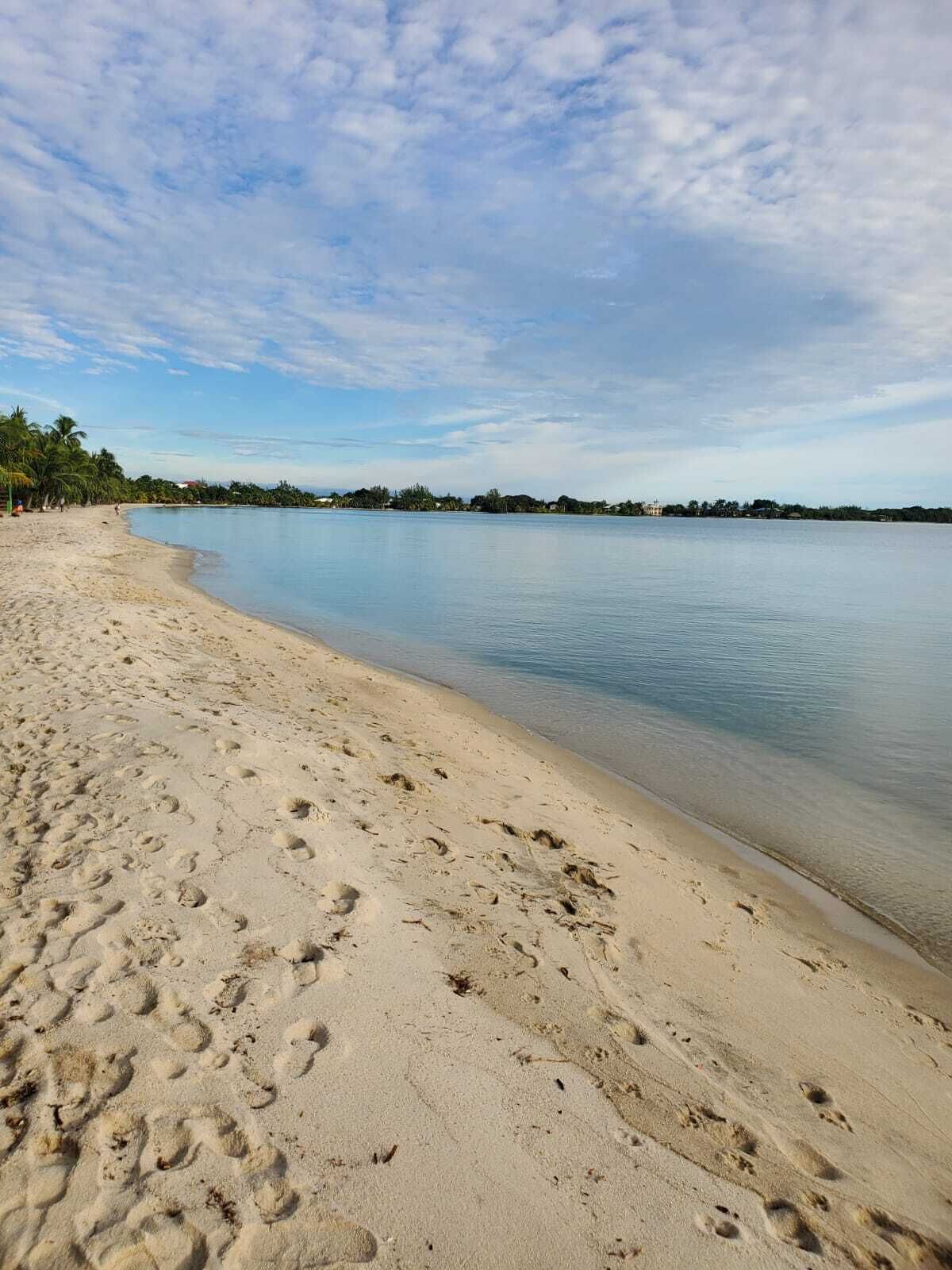 A beach with footprints in the sand and a calm sea.