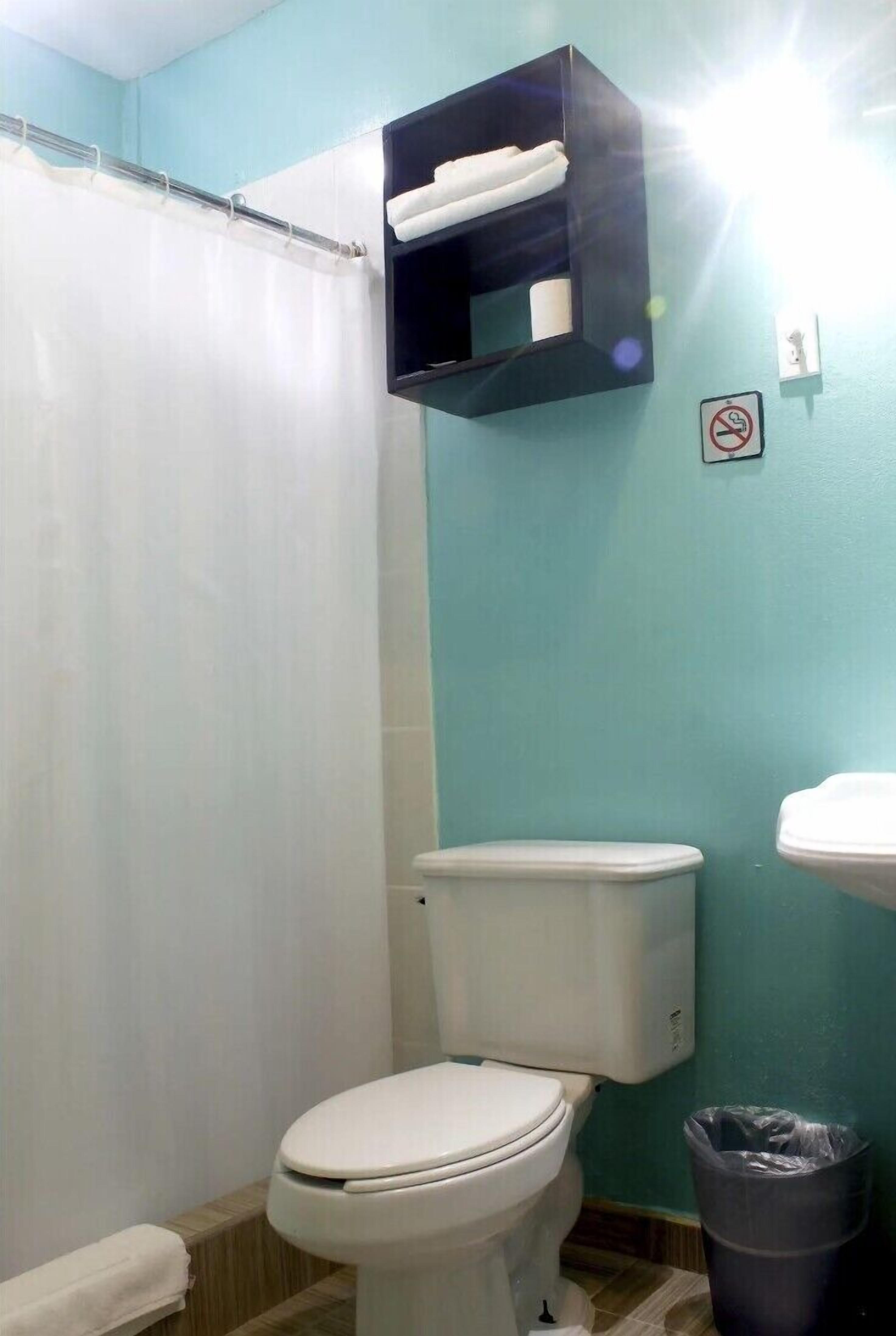 A bathroom with a toilet, a sink, a towel rack, and a trash bin.