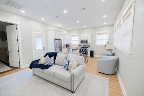 A spacious living area with a sofa, a coffee table, and a dining table. - Beautiful Walk to Downtown and Historic District (Laurel)