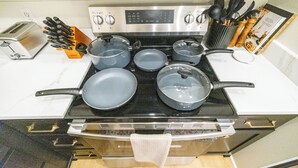 Una cocina con estufa, ollas, tostadora y un espolonador de especias.
