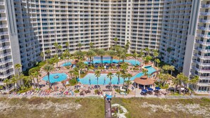 A high-rise hotel with multiple swimming pools, palm trees, and a beach area. - Shores of Panama - pools, hot tub and daily perks (Panama City Beach)